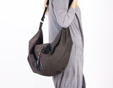 Person wearing a gray sweater with a brown hobo bag on a white background