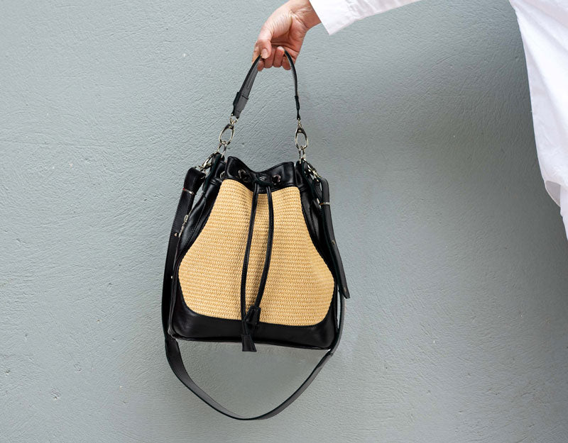 Handbag with black and beige design held against a gray background