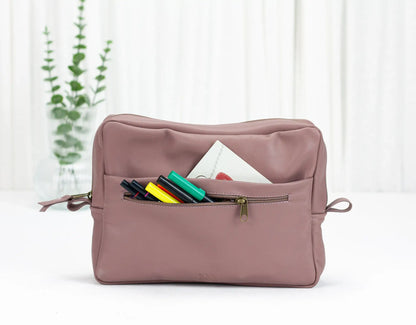 Pink toiletry bag with colorful items on a white background