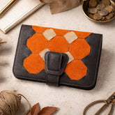 Brown and orange hexagonal patterned wallet on a light surface with coins and scissors in the background