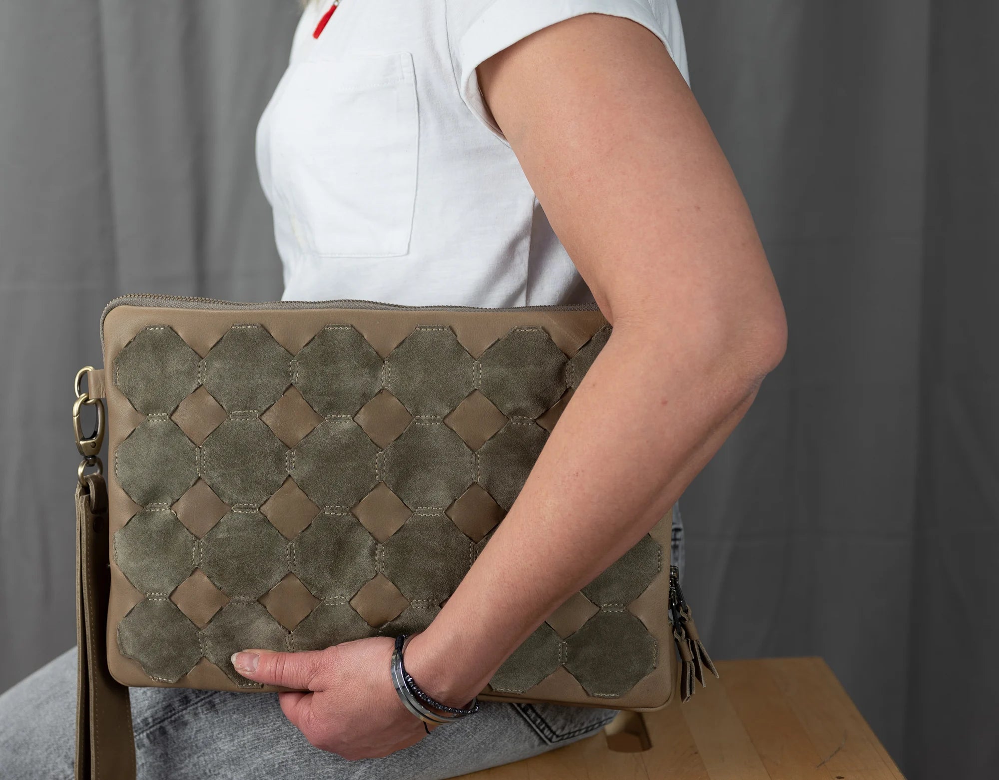 Person holding a woven leather handbag against a neutral background
