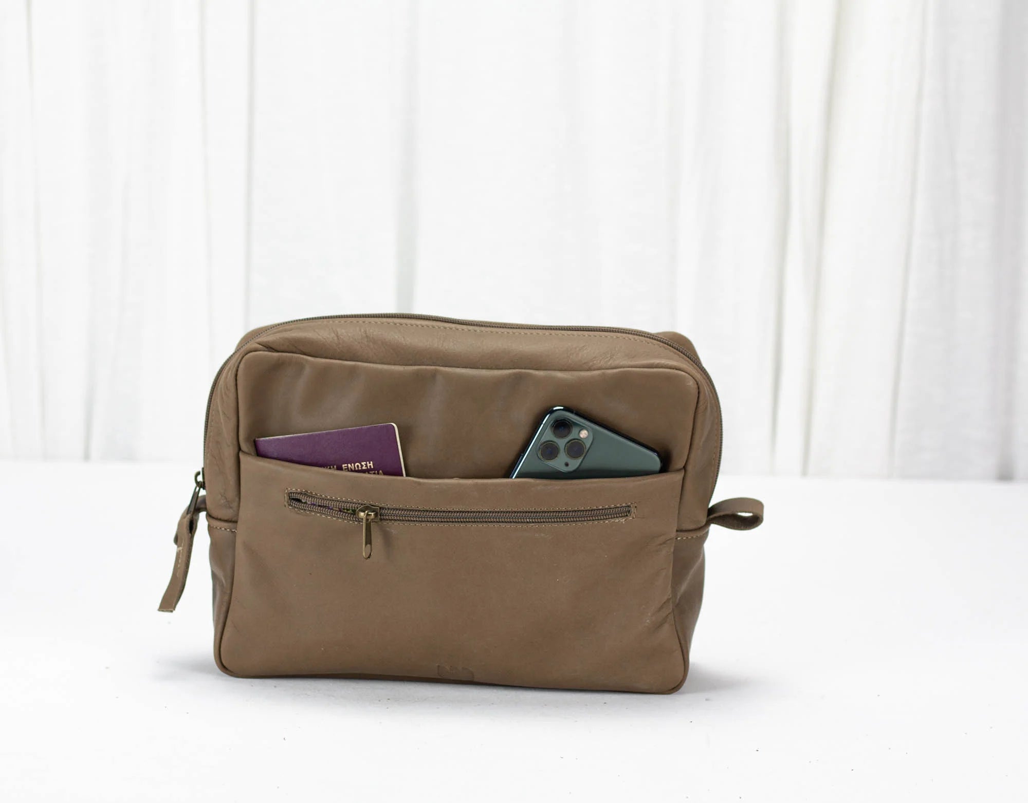 khaki Brown toiletry bag with items on a white background