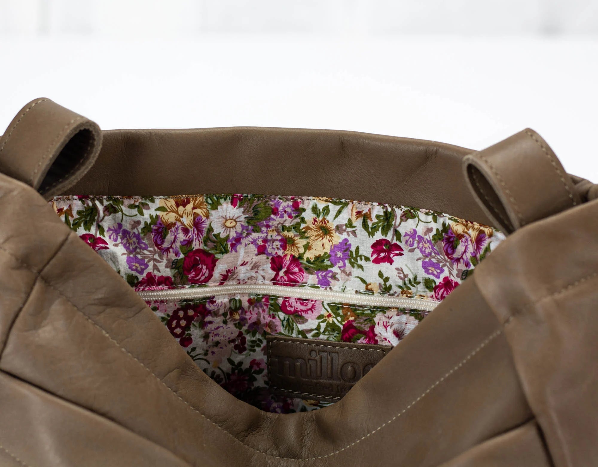 khaki Brown leather bag with floral lining on a white background