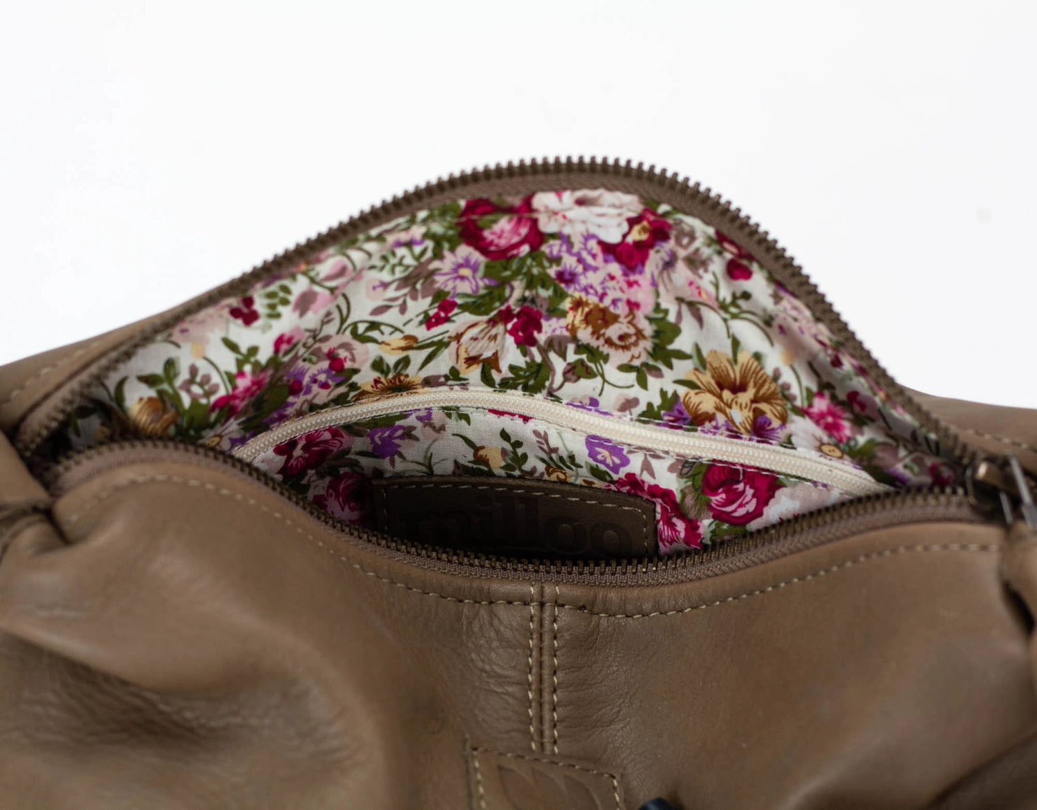 Close-up of a brown leather bag with a floral interior lining.