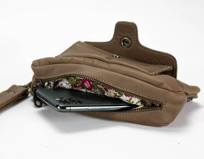 Brown leather wallet with floral lining and phone inside on a white background