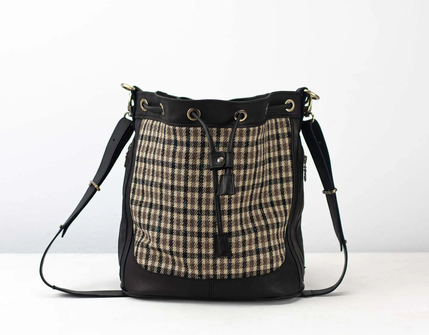 Handbag with plaid pattern and black leather accents on a white background