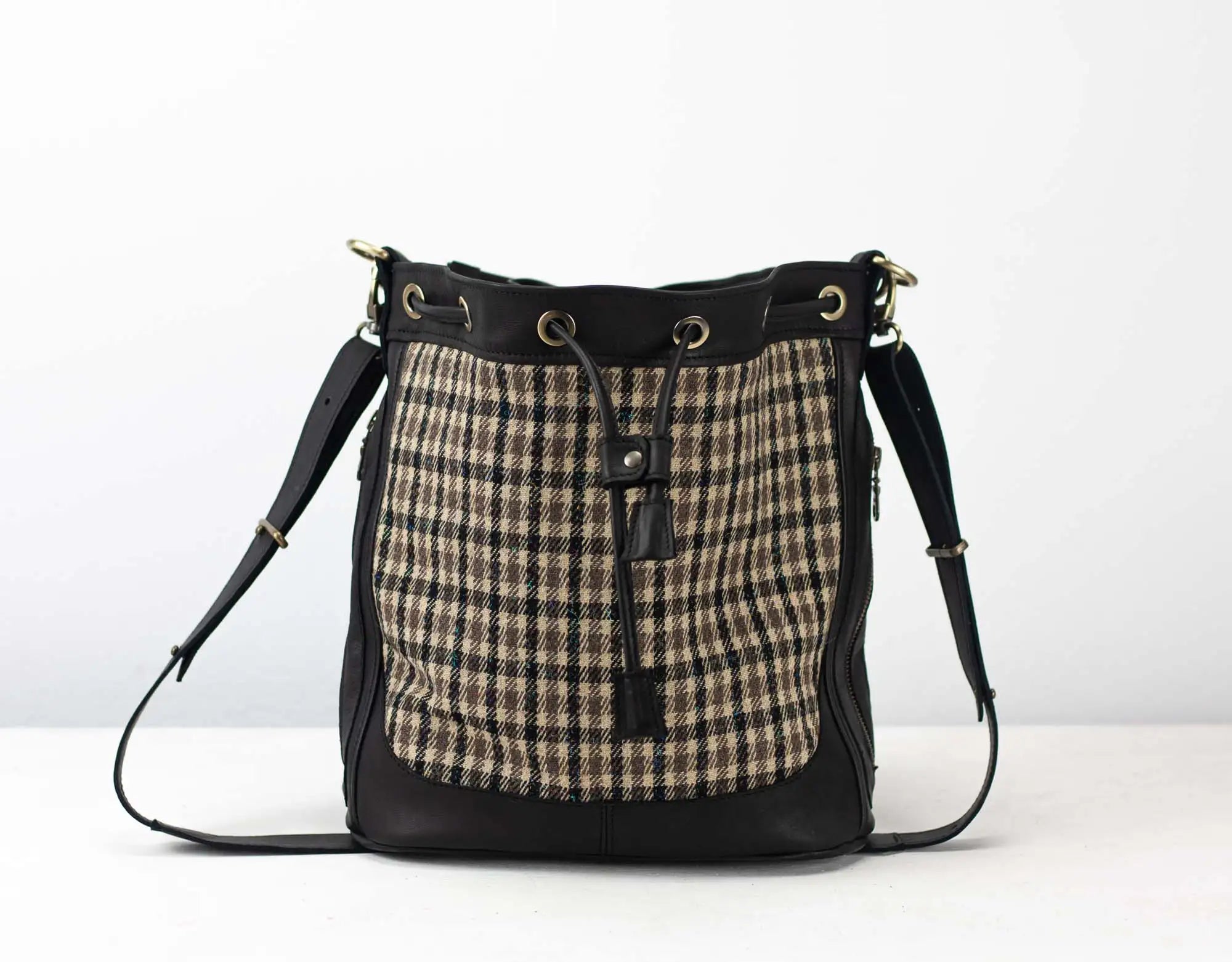 Handbag with plaid pattern and black leather accents on a white background