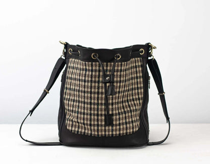 Handbag with plaid pattern and black leather accents on a white background