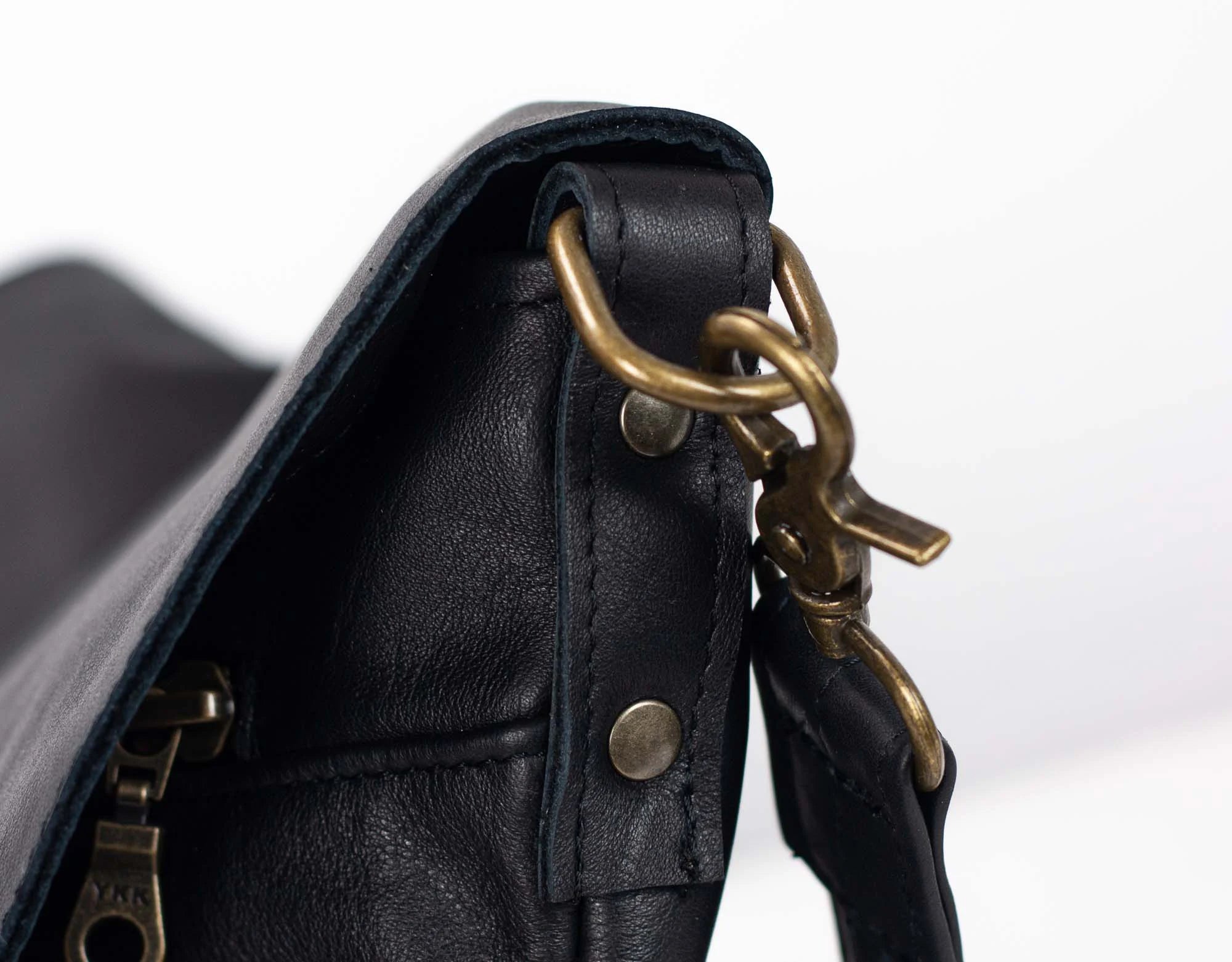 Close-up of a black leather bag with brass hardware
