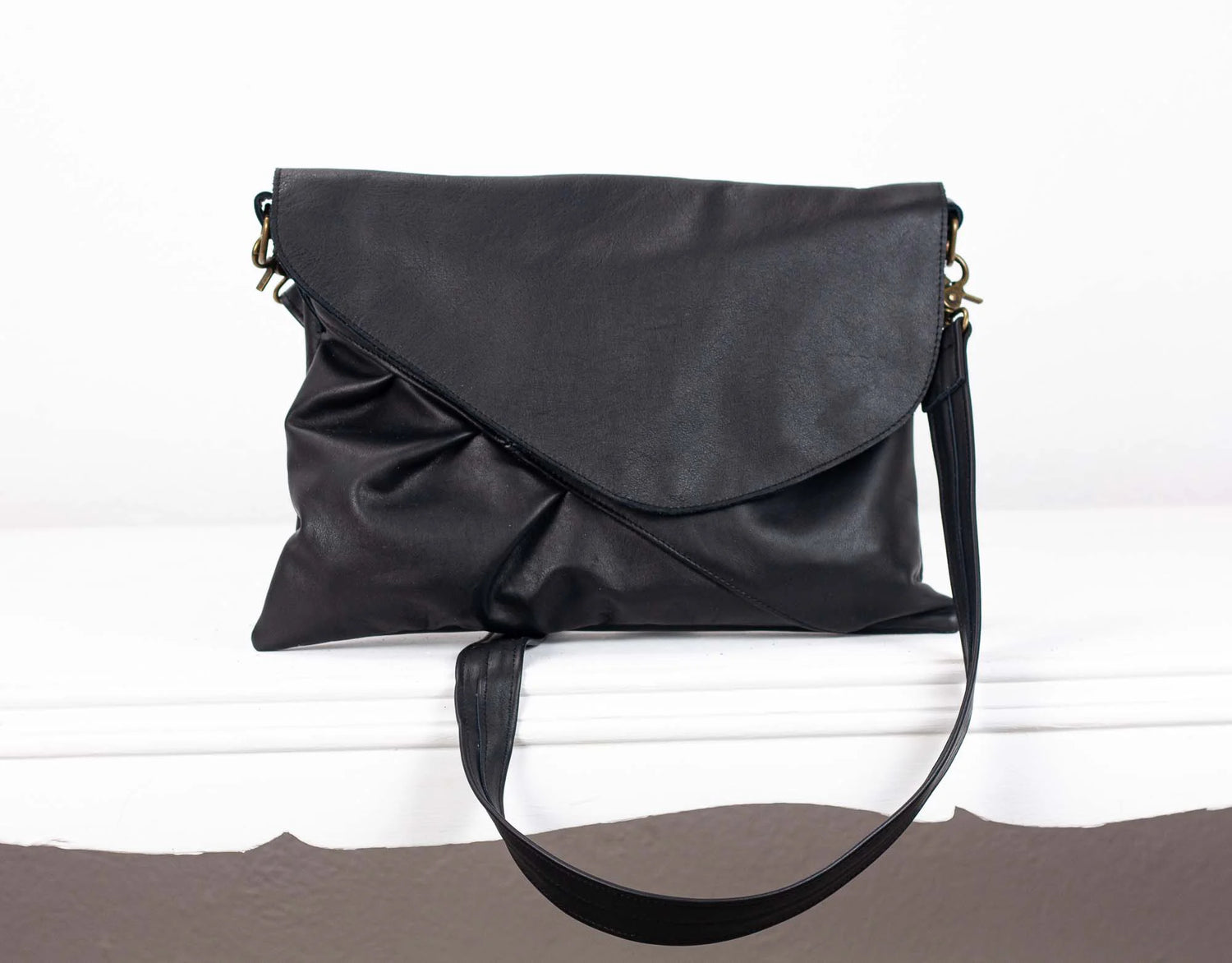 Black leather handbag on a white surface