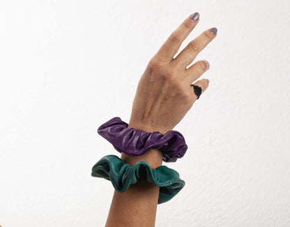 Hand wearing two scrunchies on a white background