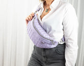 Person wearing a light purple woven waist bag against a white background