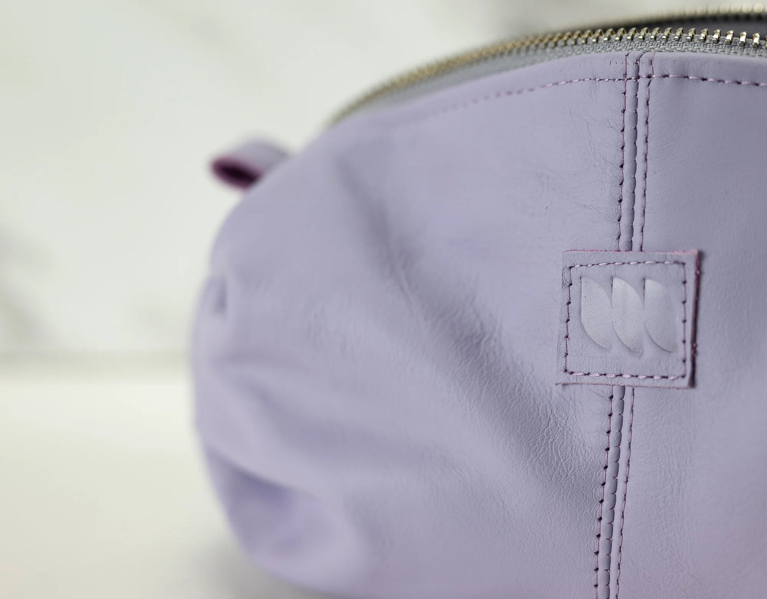 Close-up of a purple pouch with a brand logo on a light background
