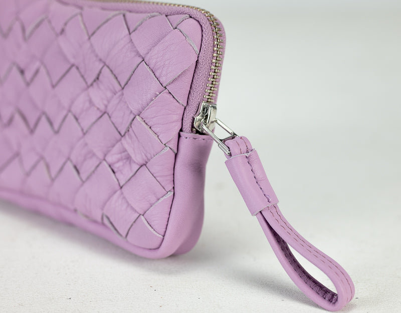 Close-up of a purple woven clutch bag with a strap on a light gray background