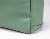 Close-up of a green leather bag corner on a white background