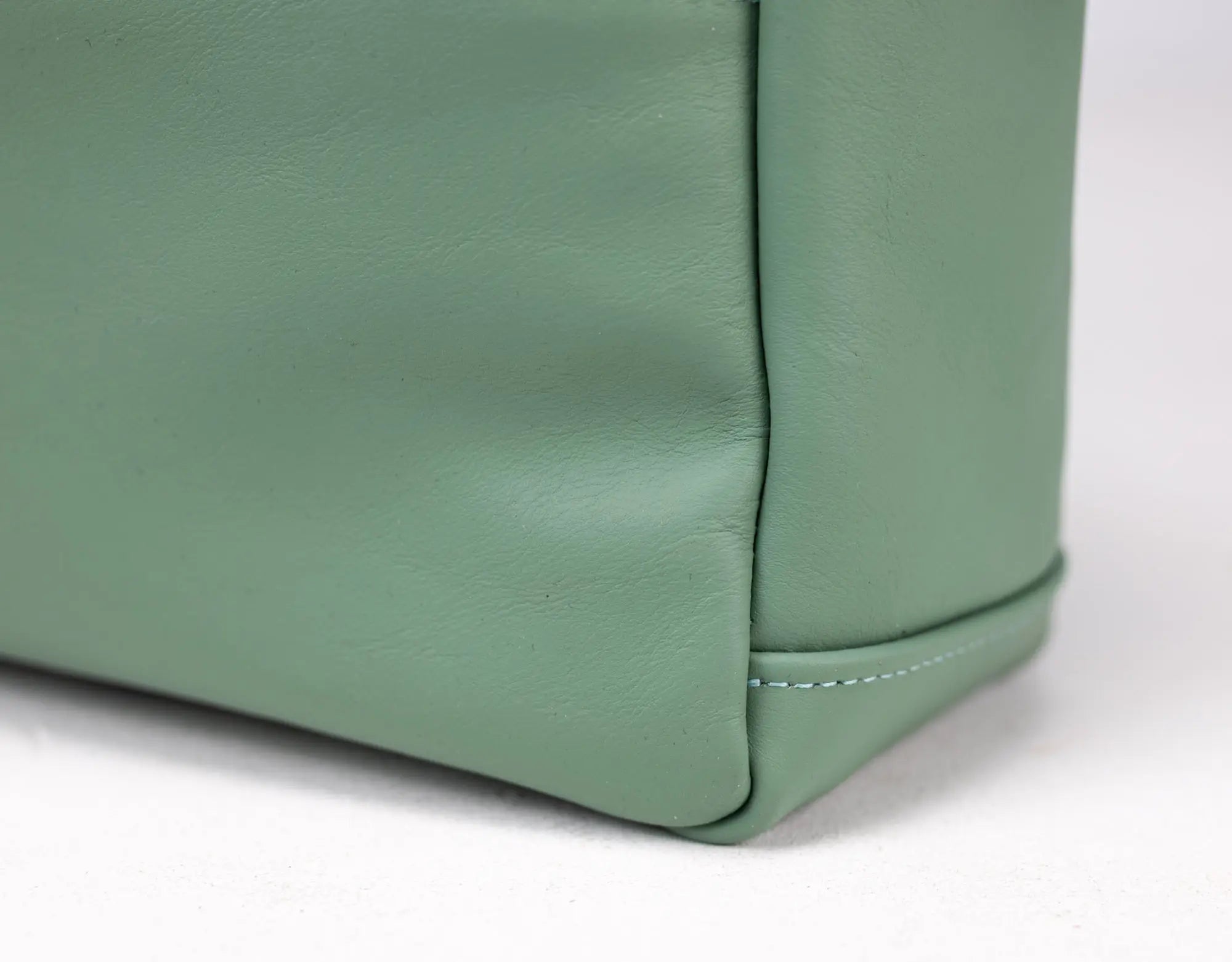 Close-up of a green leather bag corner on a white background