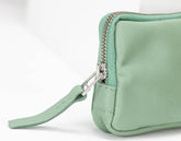 Light green clutch bag with a strap on a white background