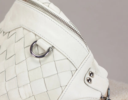 Close-up of a white quilted handbag with a metallic clasp on a neutral background