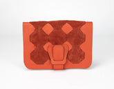 Orange suede clutch bag with geometric design on a white background