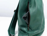 Green leather bag with a phone inside on a white background