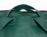 Close-up of a green leather bag with visible branding on a white background