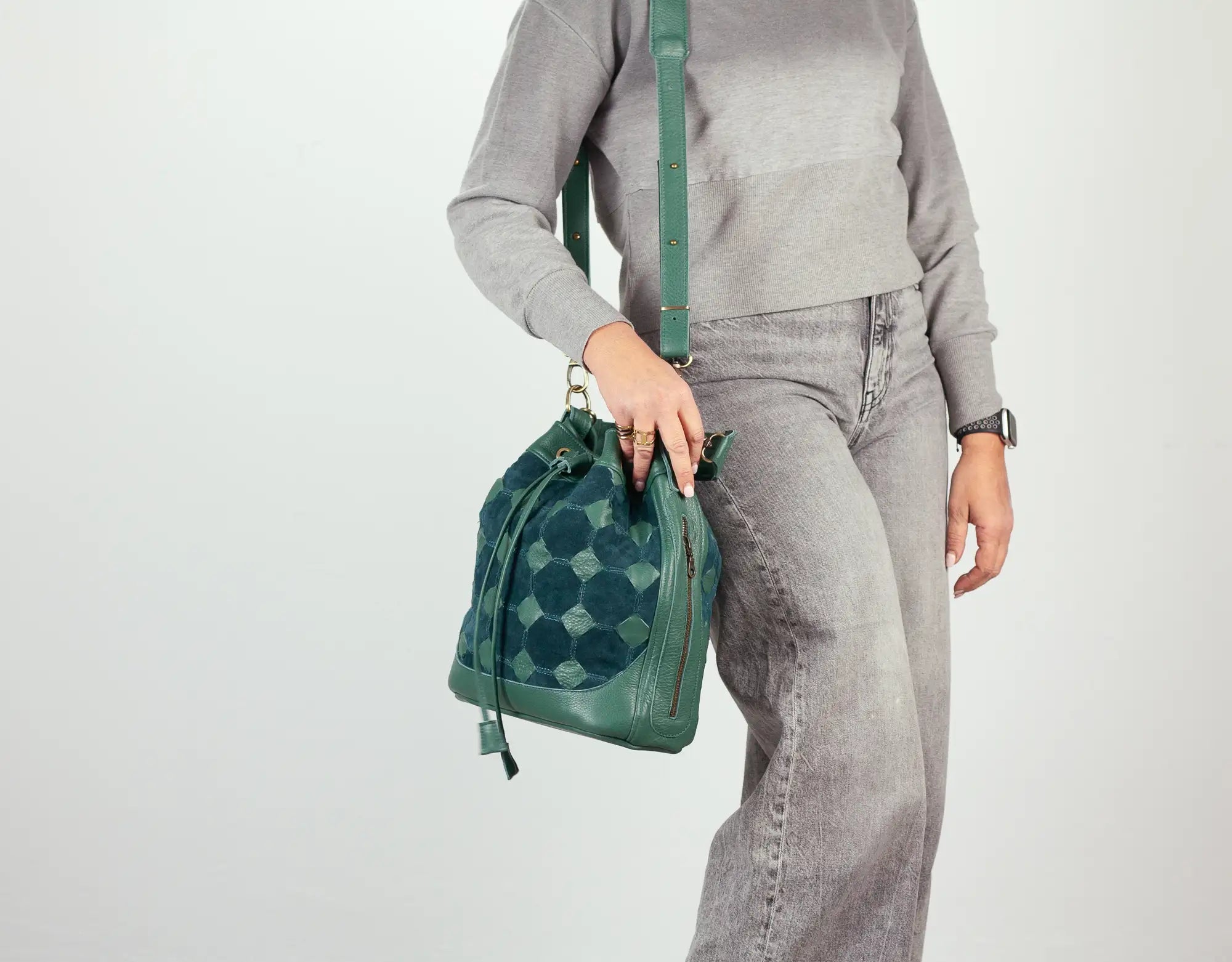Person holding a green backpack against a white background