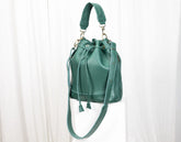 Green leather handbag with a drawstring on a white background