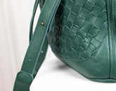 Green leather handbag with woven pattern on a white background