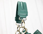 Green leather strap with gold hardware on a white background