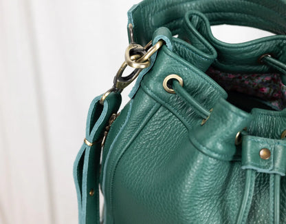 Teal leather handbag with gold hardware on a white background