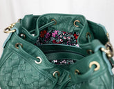Green leather handbag with floral lining on a white background