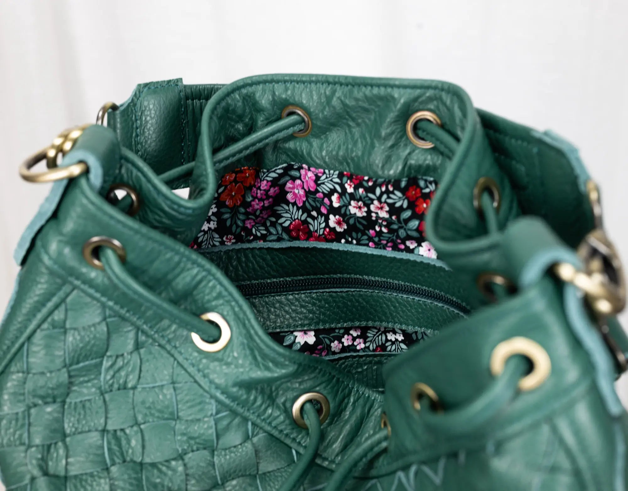 Green leather handbag with floral lining on a white background