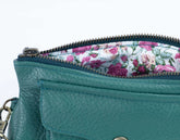 Teal handbag with floral lining on a white background