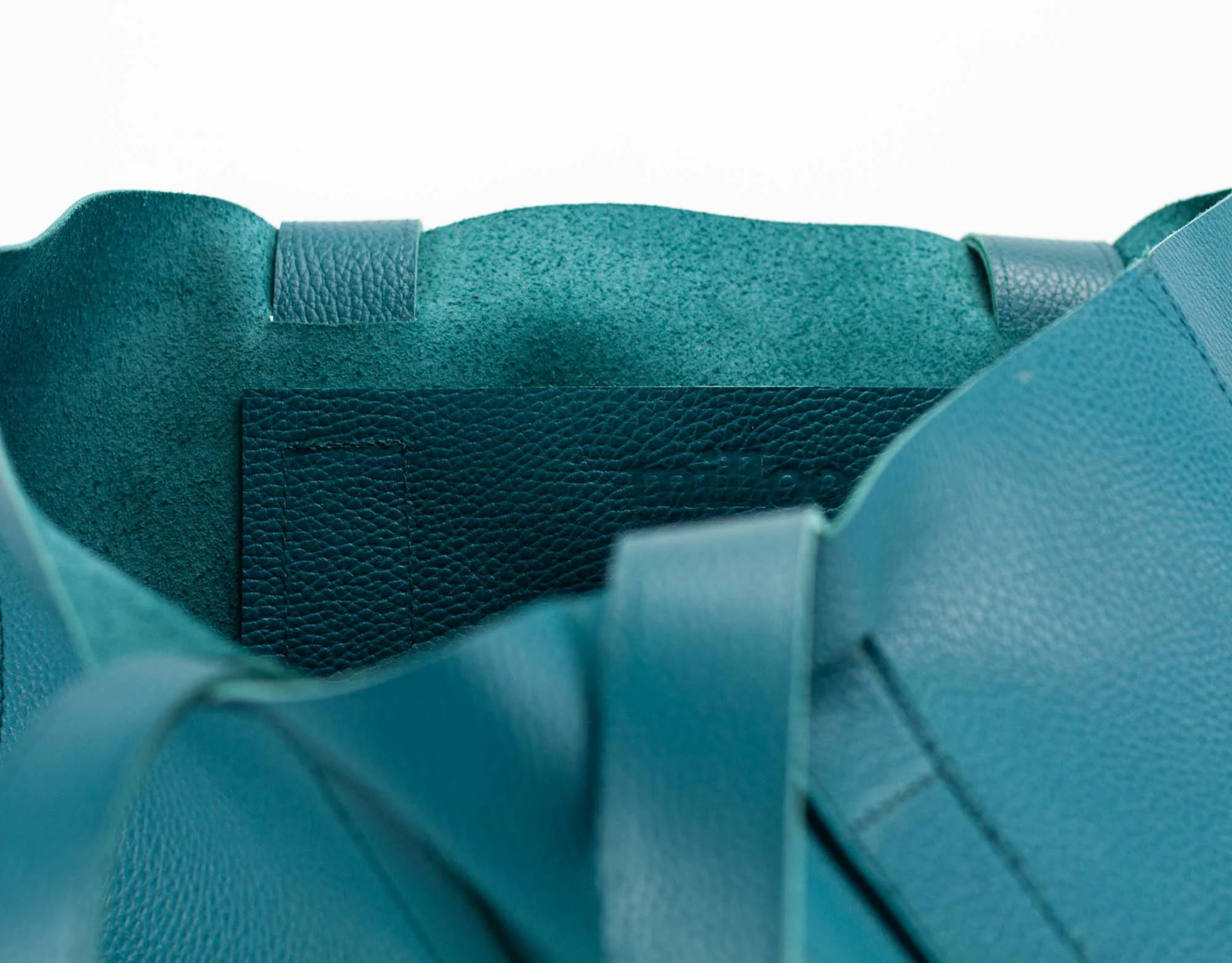 Close-up of a teal bag with a strap on a white background