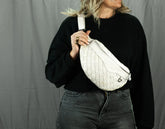 Person holding a white woven bag against a gray background