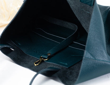 Close-up of a teal leather bag with a gold zipper on a white background