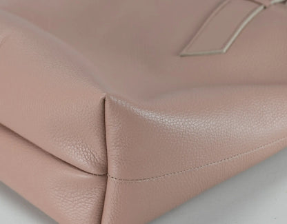 Close-up of a blush pink pebbled leather handbag corner showing the texture and stitching detail.