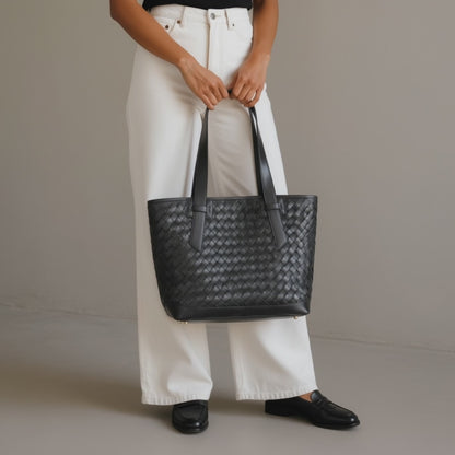 A woman carrying a black leather tote bag