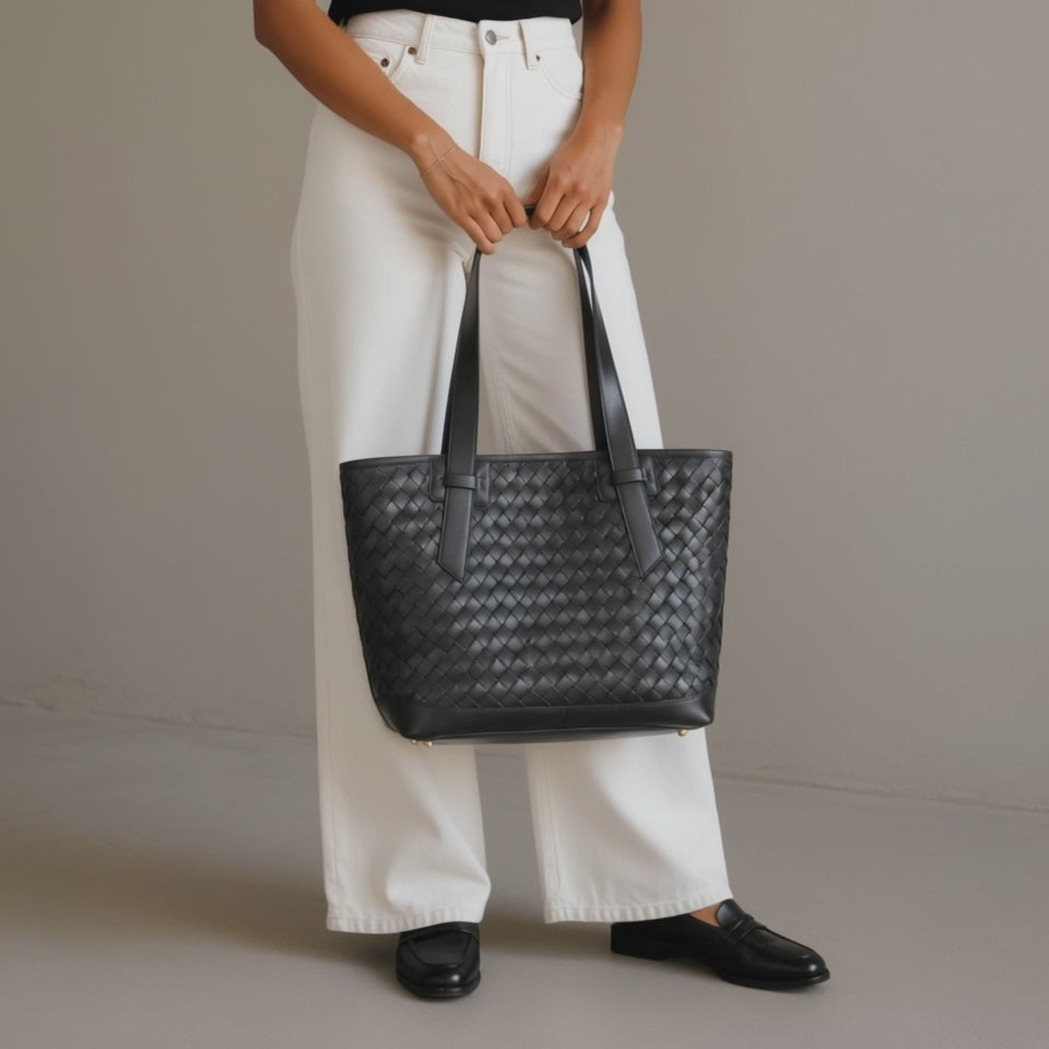 A woman carrying a black leather tote bag