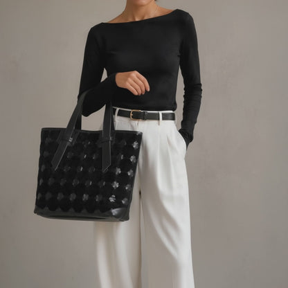 A woman carrying a black leather tote bag