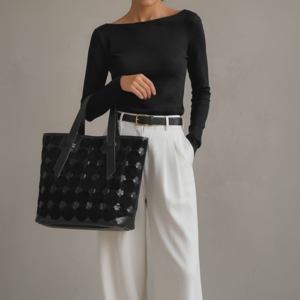 A woman carrying a black leather tote bag