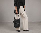 a woman carrying a black woven leather bag by milloo