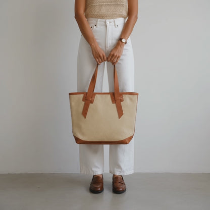 A woman carrying a cream tote bag