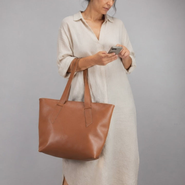 A woman carrying a brown leather tote bag