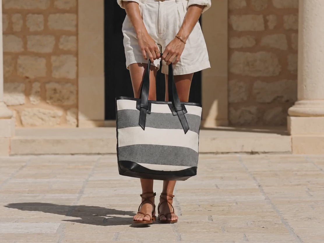 A woman carrying a stripe tote bag