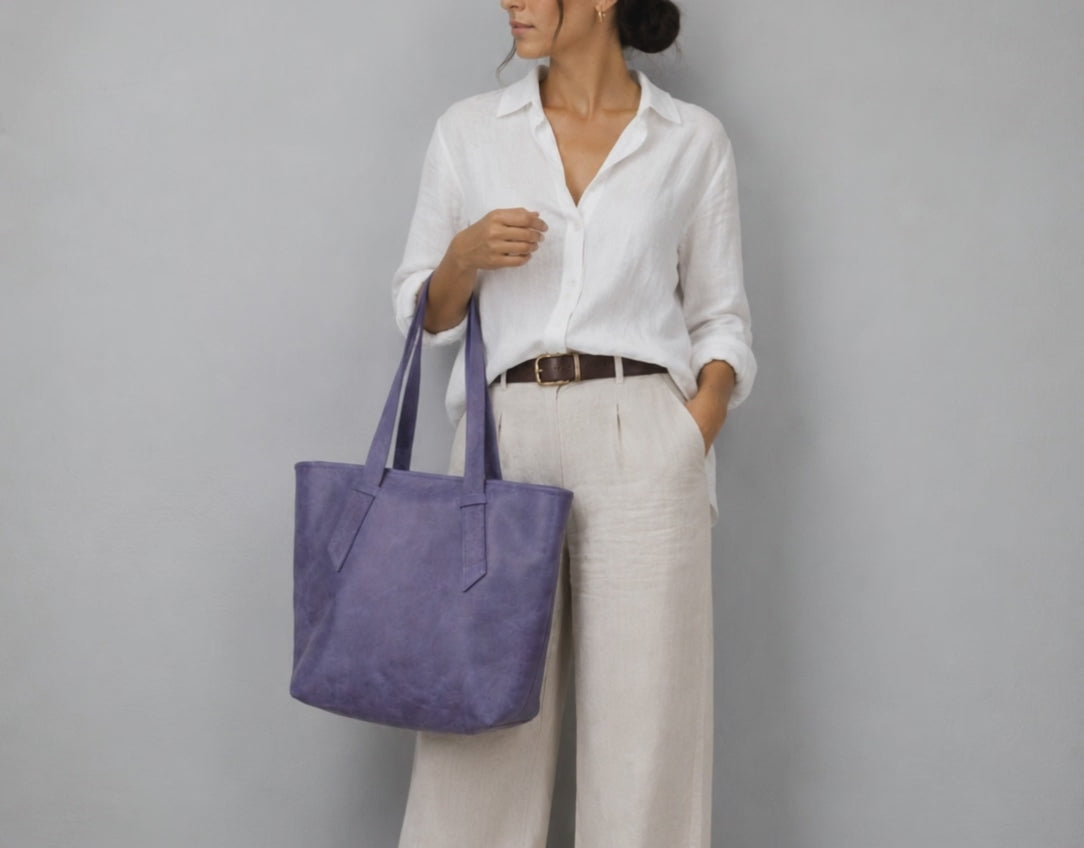 A woman holding a purple leather tote bag 