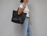 A woman carrying a black leather tote bag