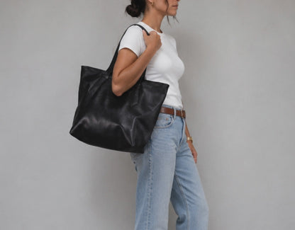 A woman carrying a black leather tote bag
