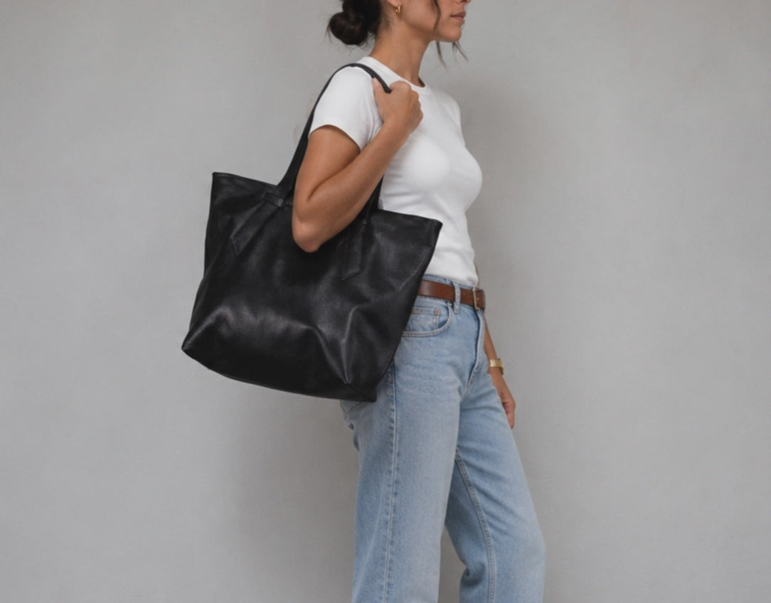A woman carrying a black leather tote bag