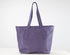 A purple leather tote bag with two shoulder straps, displayed against a clean white studio background.